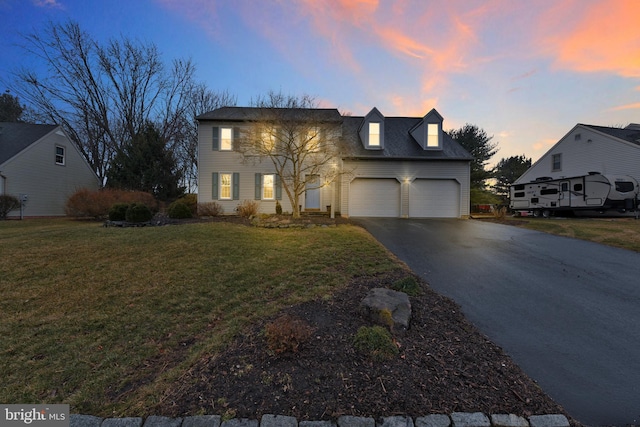 view of front of house featuring driveway, a garage, and a yard