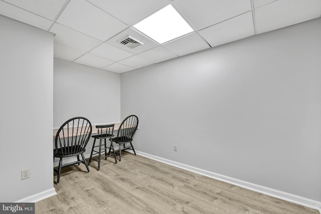 living area featuring baseboards, visible vents, a drop ceiling, and wood finished floors