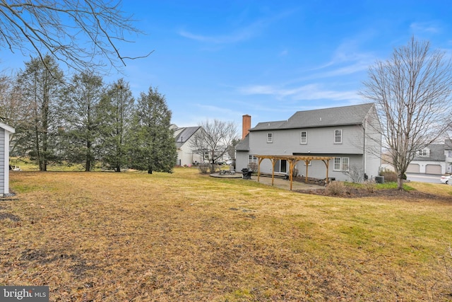 rear view of property with a yard, a chimney, and a patio