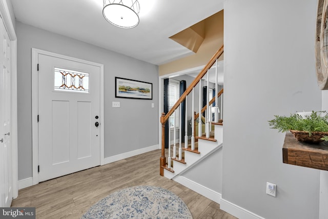 foyer entrance with baseboards, stairway, and wood finished floors