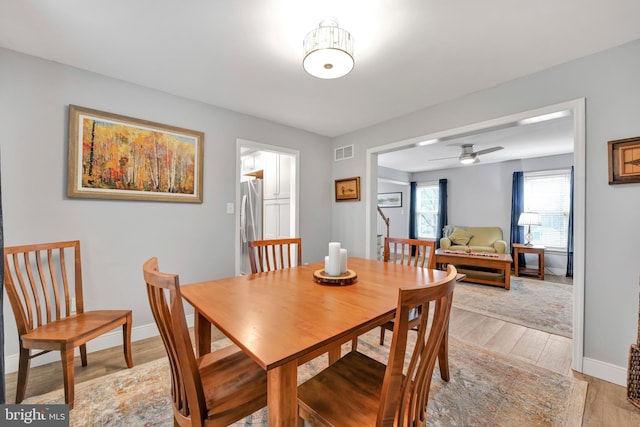 dining room featuring light wood-type flooring, baseboards, visible vents, and ceiling fan