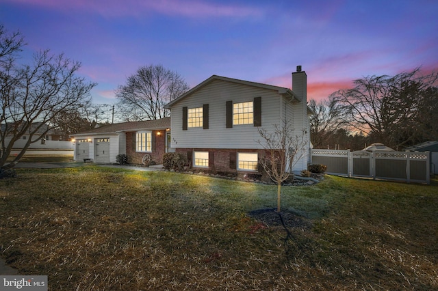 view of front of home with an attached garage, fence, a lawn, a gate, and a chimney