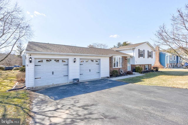 split level home with a garage, aphalt driveway, and a front yard