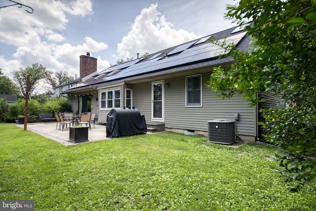 rear view of house featuring cooling unit, a yard, a patio, and solar panels