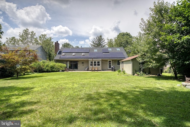 rear view of property featuring a shed, a yard, a patio area, and solar panels