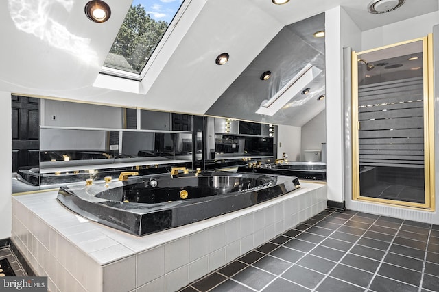 kitchen with tile countertops, vaulted ceiling with skylight, and dark tile patterned floors