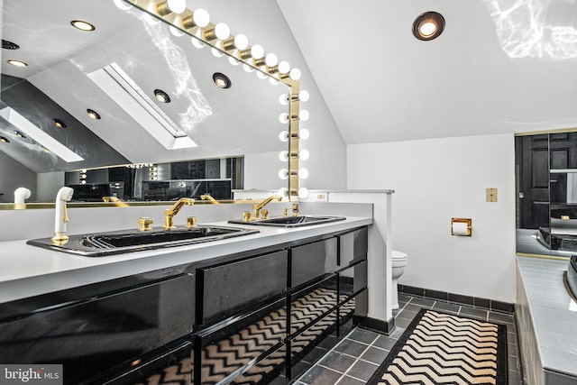 bathroom featuring lofted ceiling with skylight, vanity, tile patterned floors, and toilet