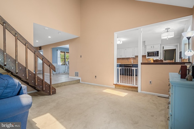 carpeted living room with high vaulted ceiling