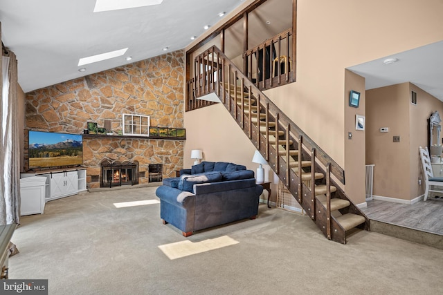 living room featuring carpet flooring, a skylight, high vaulted ceiling, and a stone fireplace