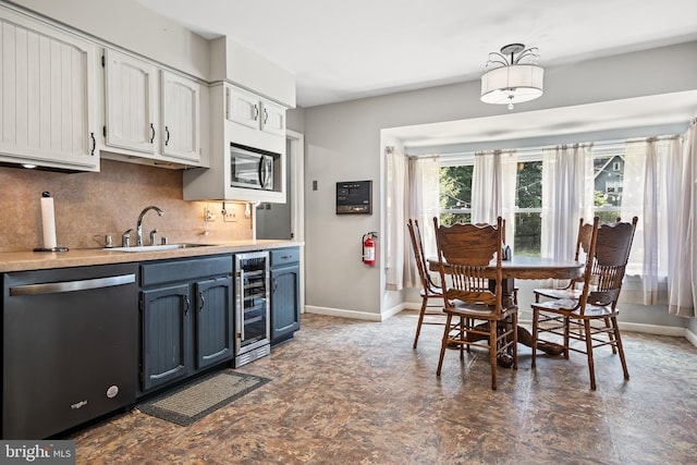 kitchen with blue cabinetry, sink, stainless steel dishwasher, beverage cooler, and white cabinets