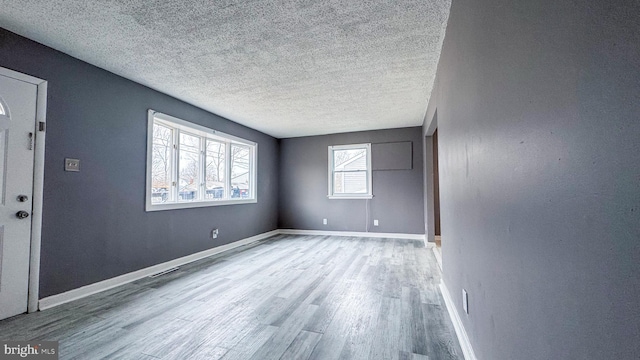 empty room featuring a textured ceiling and light hardwood / wood-style flooring