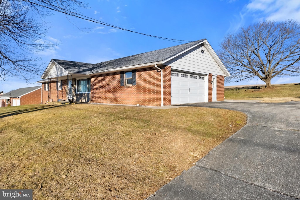 view of home's exterior with aphalt driveway, brick siding, a yard, roof with shingles, and a garage