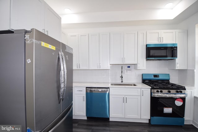 kitchen with stainless steel appliances, white cabinetry, sink, and decorative backsplash