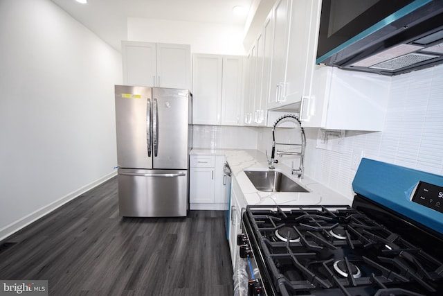 kitchen featuring appliances with stainless steel finishes, sink, white cabinets, light stone countertops, and dark wood-type flooring