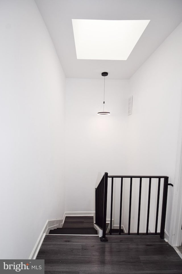 staircase with hardwood / wood-style flooring and a skylight