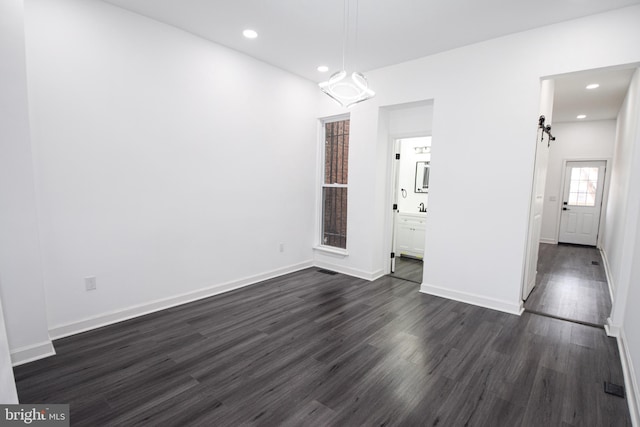 empty room featuring a barn door and dark hardwood / wood-style flooring