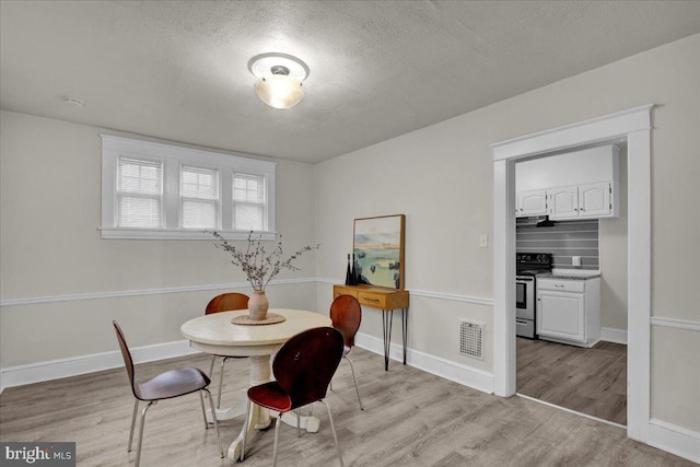 dining space featuring light hardwood / wood-style flooring and a textured ceiling