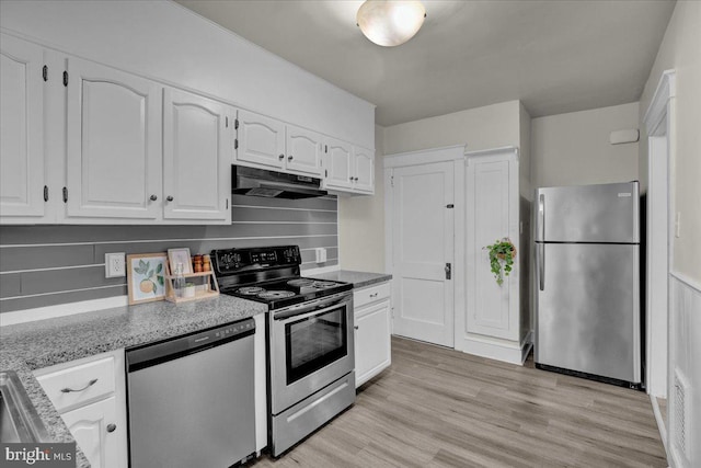 kitchen featuring light wood-type flooring, light stone countertops, white cabinets, and appliances with stainless steel finishes