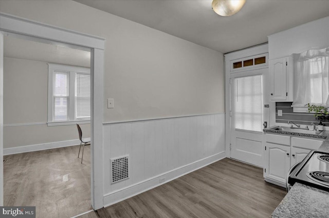 kitchen with sink, electric range, white cabinets, and light wood-type flooring