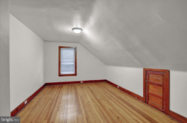 additional living space featuring vaulted ceiling and light hardwood / wood-style floors