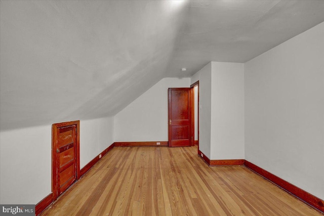 bonus room with lofted ceiling and light wood-type flooring