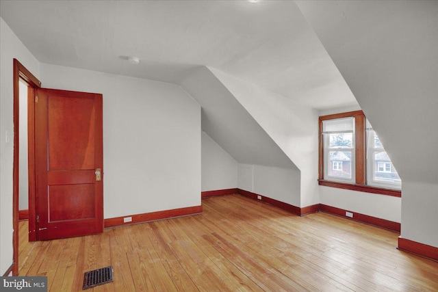 additional living space with vaulted ceiling and light hardwood / wood-style flooring