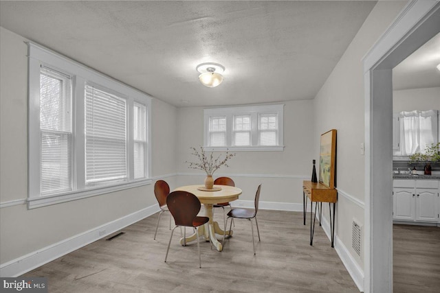 dining area featuring a textured ceiling and light hardwood / wood-style flooring