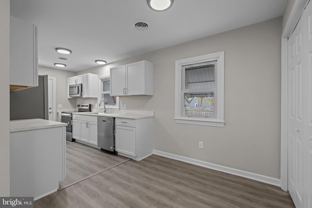 kitchen featuring white cabinetry, stainless steel appliances, sink, and light wood-type flooring