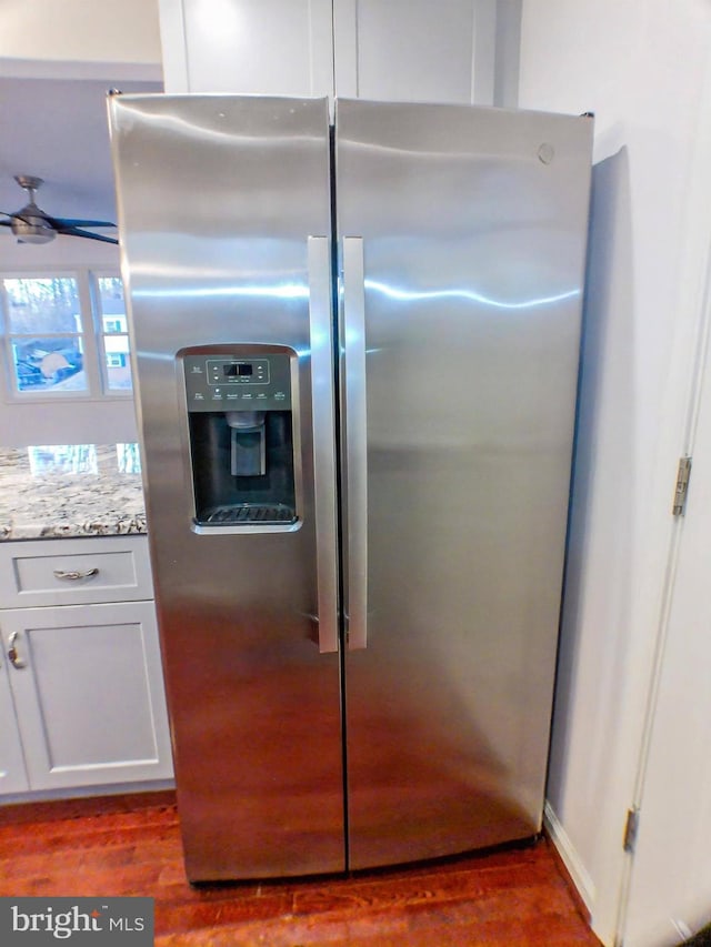 interior details featuring light stone counters, stainless steel fridge, dark wood-type flooring, and white cabinets