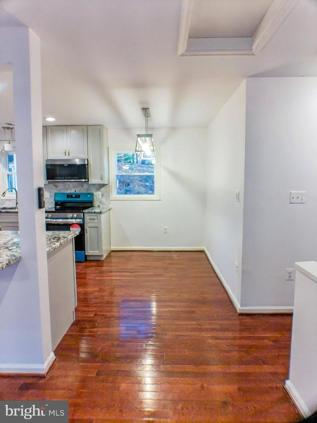 kitchen with sink, hanging light fixtures, appliances with stainless steel finishes, dark hardwood / wood-style floors, and decorative backsplash