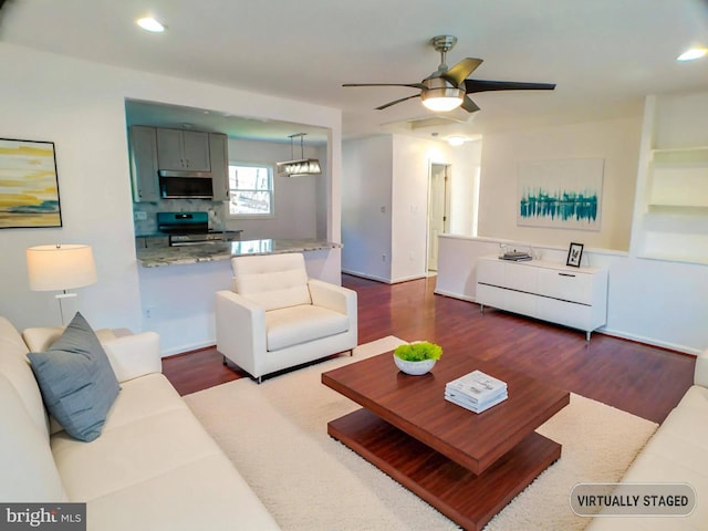 living room featuring dark wood-type flooring and ceiling fan