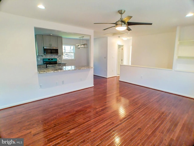 unfurnished living room featuring ceiling fan and dark hardwood / wood-style flooring