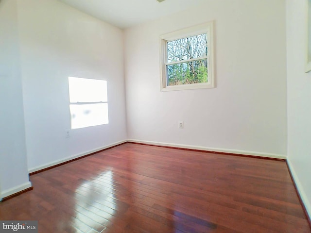 empty room with dark hardwood / wood-style flooring and a wealth of natural light