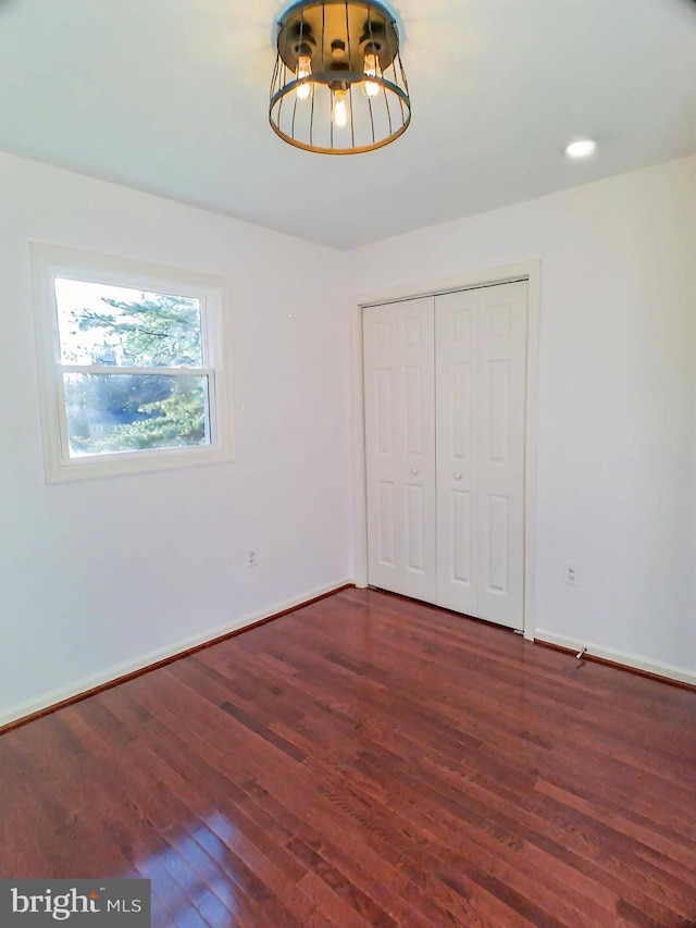 unfurnished bedroom featuring dark hardwood / wood-style floors and a closet