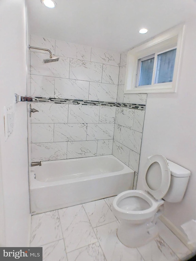 bathroom featuring tiled shower / bath combo and toilet