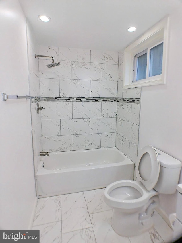 bathroom featuring tiled shower / bath combo and toilet