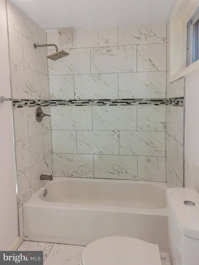 bathroom featuring tiled shower / bath and toilet