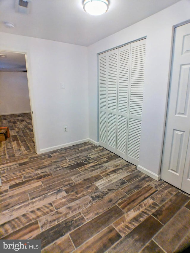 unfurnished bedroom featuring dark hardwood / wood-style flooring and a closet