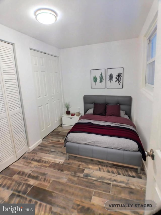 bedroom with dark hardwood / wood-style floors and two closets