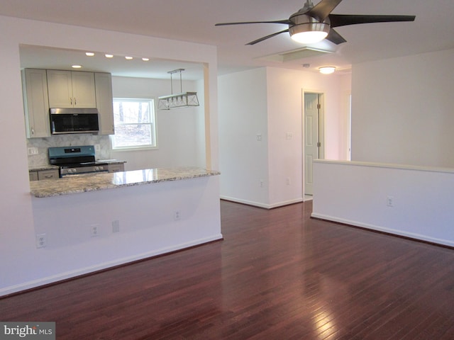 kitchen with ceiling fan, stainless steel appliances, dark hardwood / wood-style floors, light stone counters, and decorative backsplash