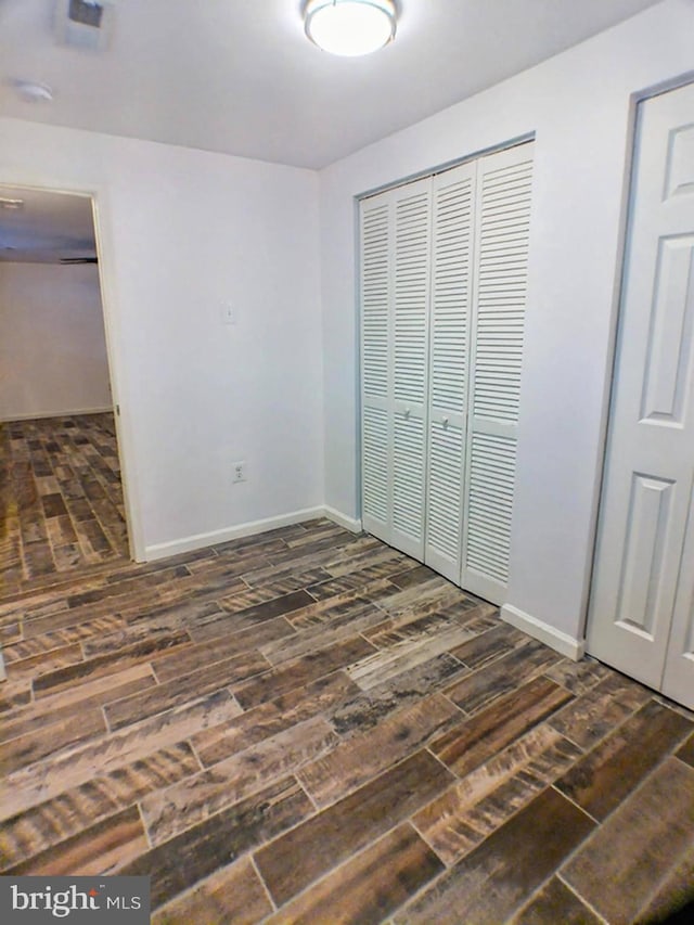 unfurnished bedroom with dark hardwood / wood-style floors and a closet