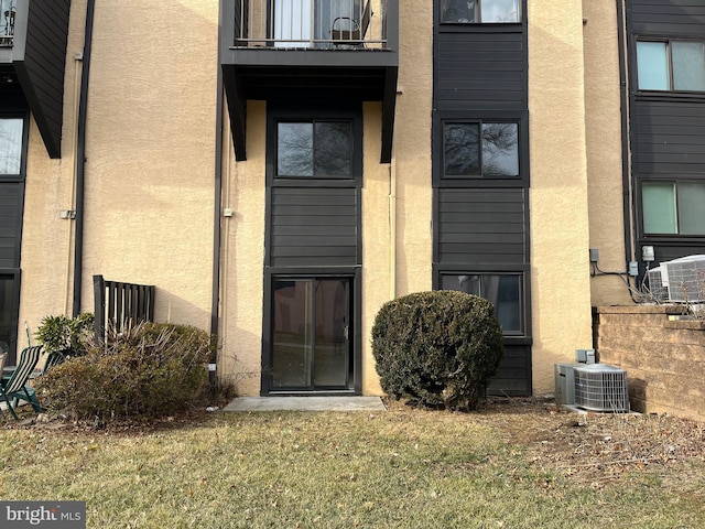 doorway to property with a balcony, a yard, and central air condition unit