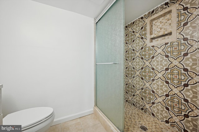 bathroom with tile patterned floors, toilet, and a shower with shower door