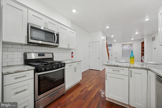 kitchen with appliances with stainless steel finishes, white cabinets, and light stone counters