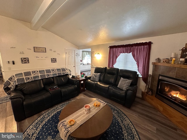 living room with a tiled fireplace, vaulted ceiling with beams, and hardwood / wood-style floors