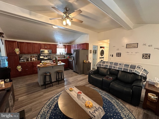 living room featuring stacked washer and dryer, ceiling fan, vaulted ceiling with beams, and dark hardwood / wood-style floors