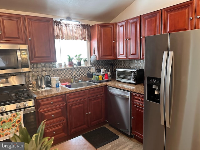 kitchen with tasteful backsplash, light stone countertops, appliances with stainless steel finishes, and sink