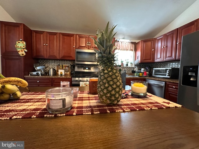 kitchen with tasteful backsplash, vaulted ceiling, and appliances with stainless steel finishes