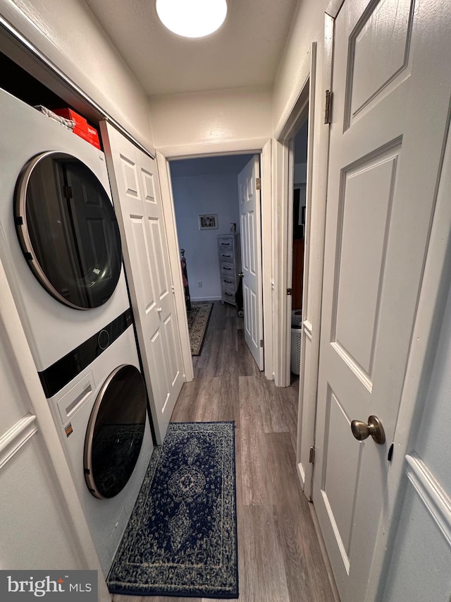 laundry room with stacked washer / dryer and hardwood / wood-style flooring