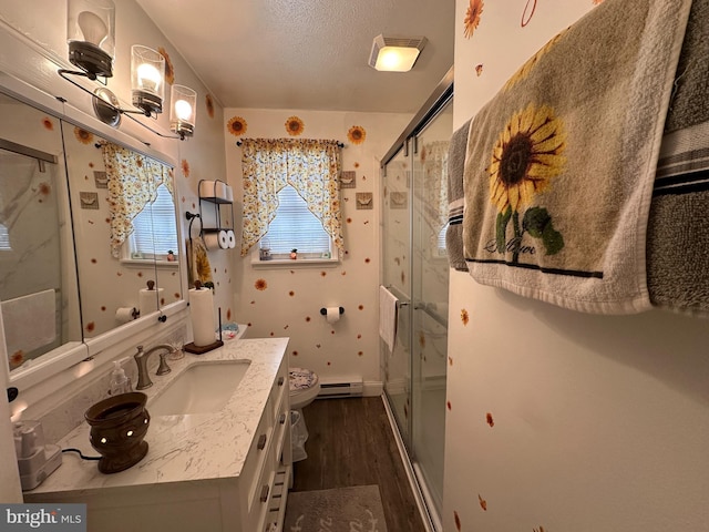 bathroom featuring vanity, an enclosed shower, hardwood / wood-style floors, and baseboard heating